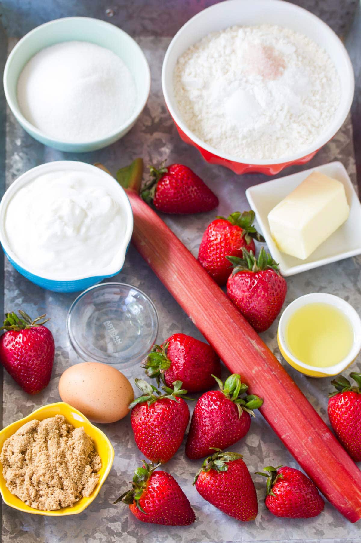 Measured out ingredients to make strawberry rhubarb muffins on a metal baking tray.