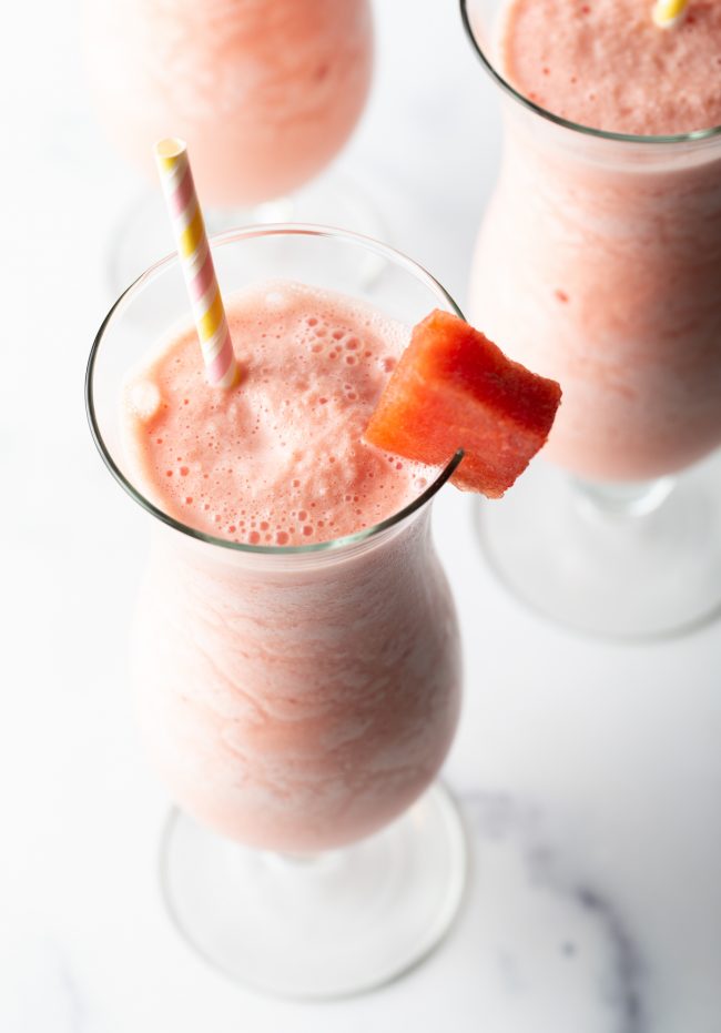 a watermelon smoothie with cube of watermelon and straw