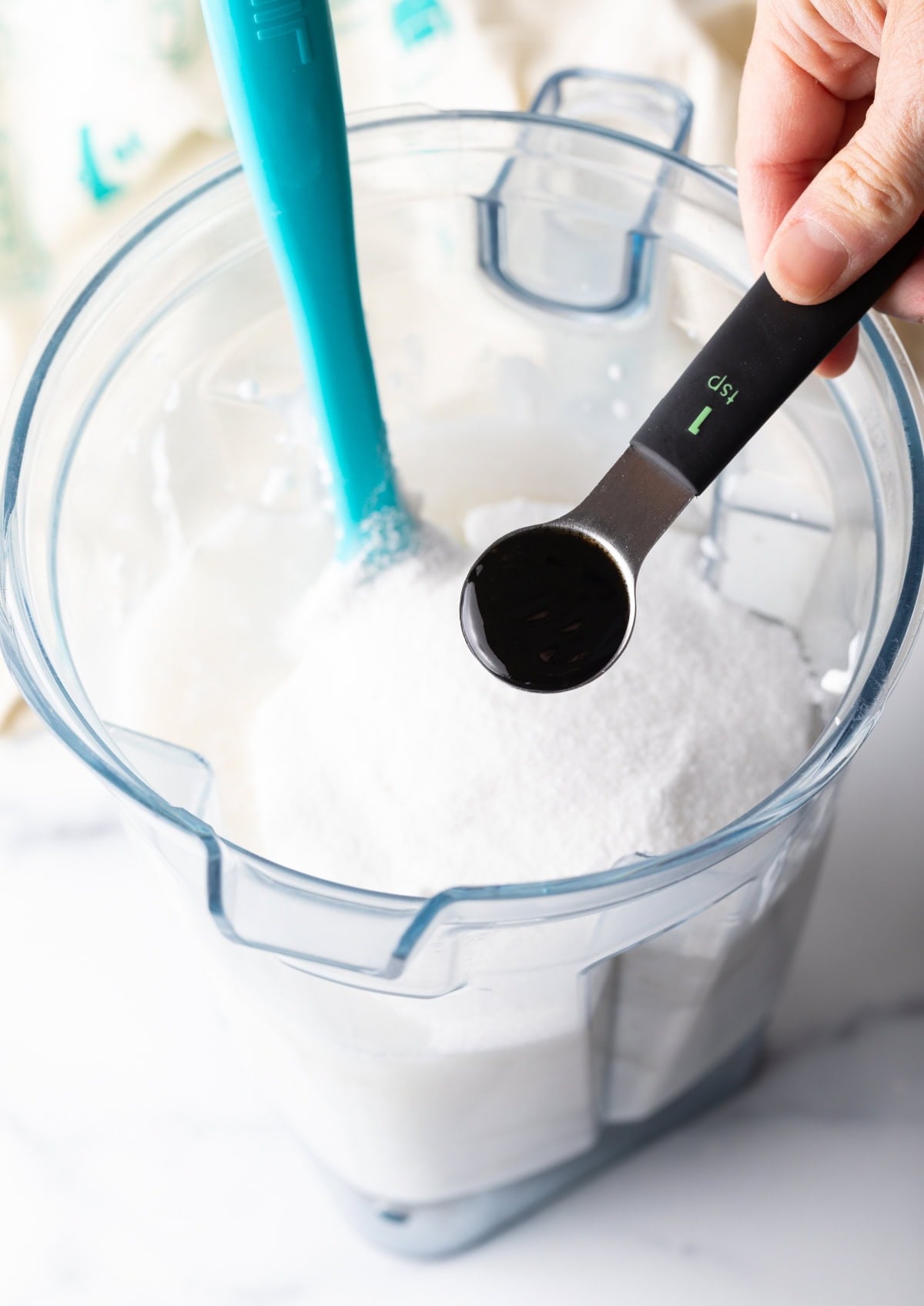 adding vanilla to the blender with coconut milk in it.