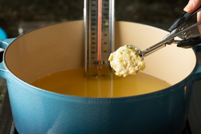 scooping the batter into hot oil for frying