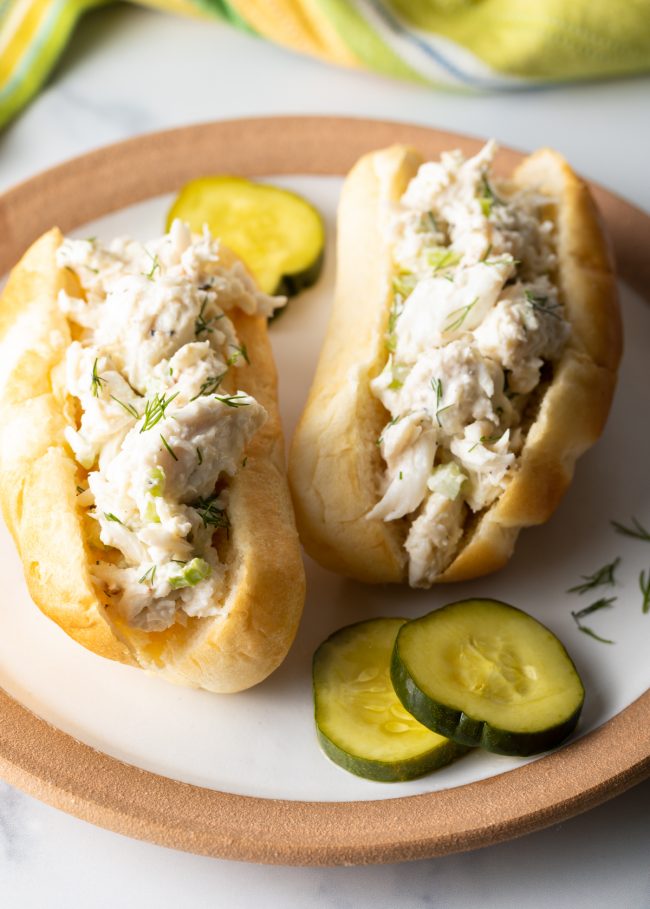 crab roll sandwiches with pickles on a plate