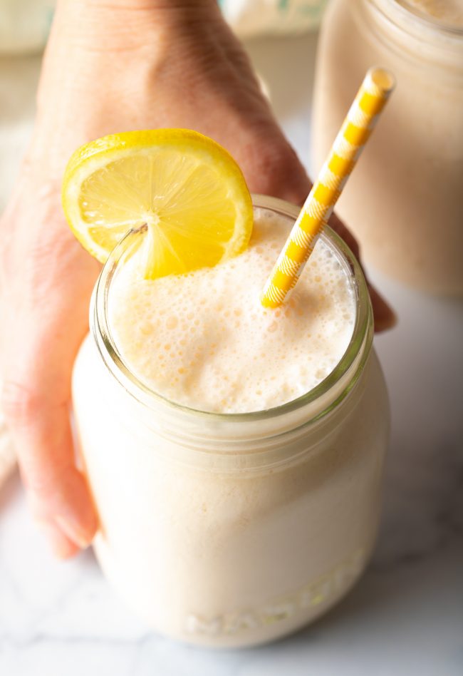 hand with glass of freshly made frozen lemonade recipe