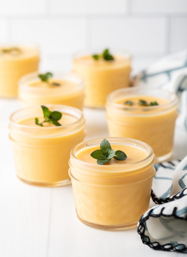 lined up cups of dairy free mango pudding with mint garnishes