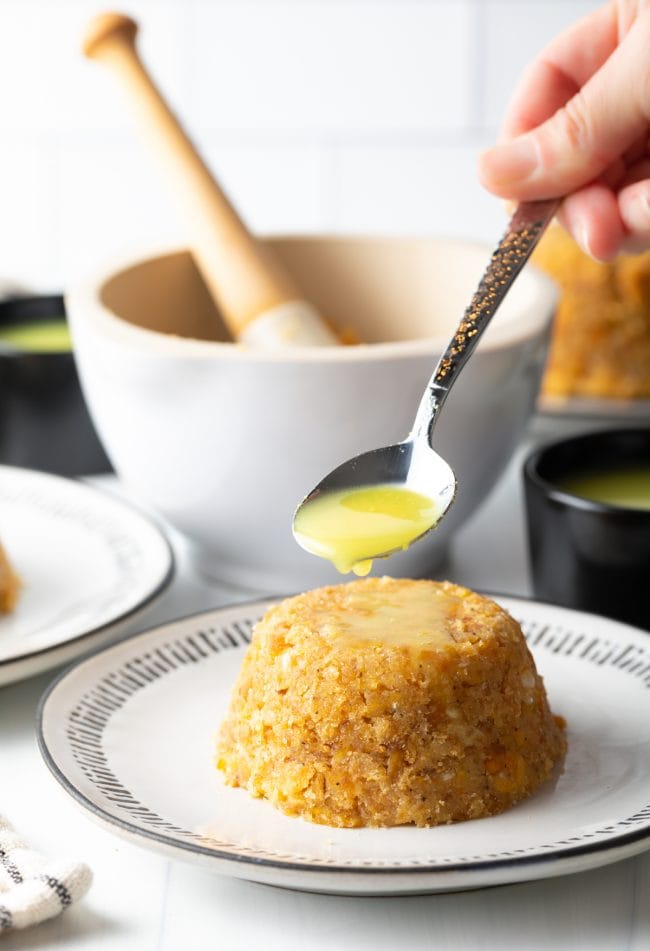 Shaped mofongo on a plate being topped with sauce. 