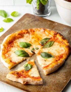 Baked Neapolitan pizza with fresh basil leaves.