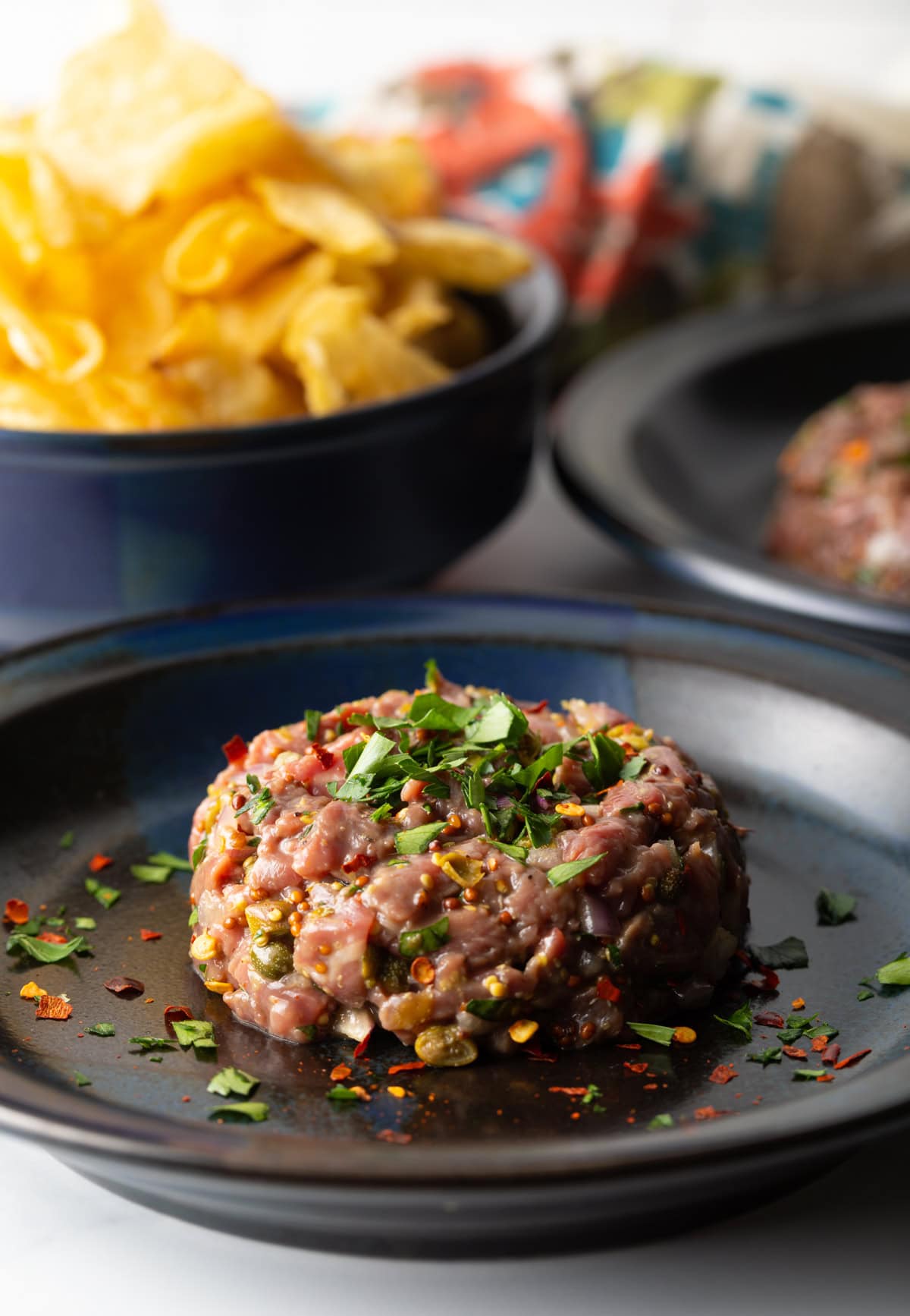 Plated steak tartare topped with fresh herbs.