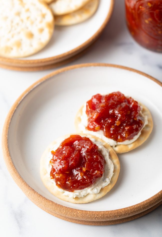 overhead view of plate with two crackers, with cheese and dollop of tomato jam