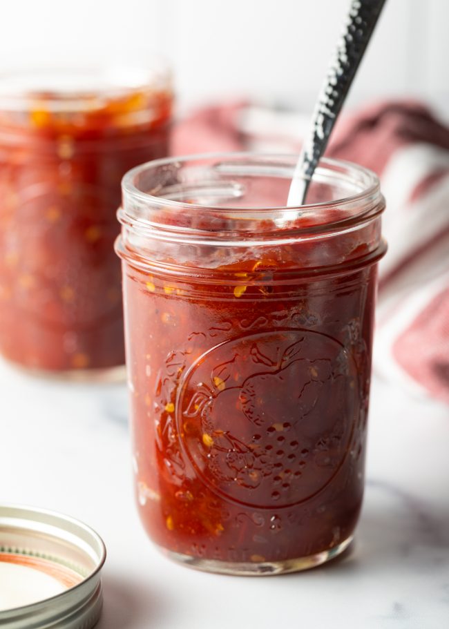full jar of homemade tomato jam with spoon in it