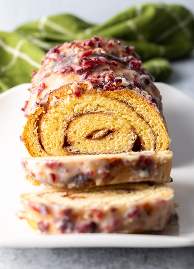 cranberry lemon glazed cinnamon swirl bread on a white plate with two slices to the side