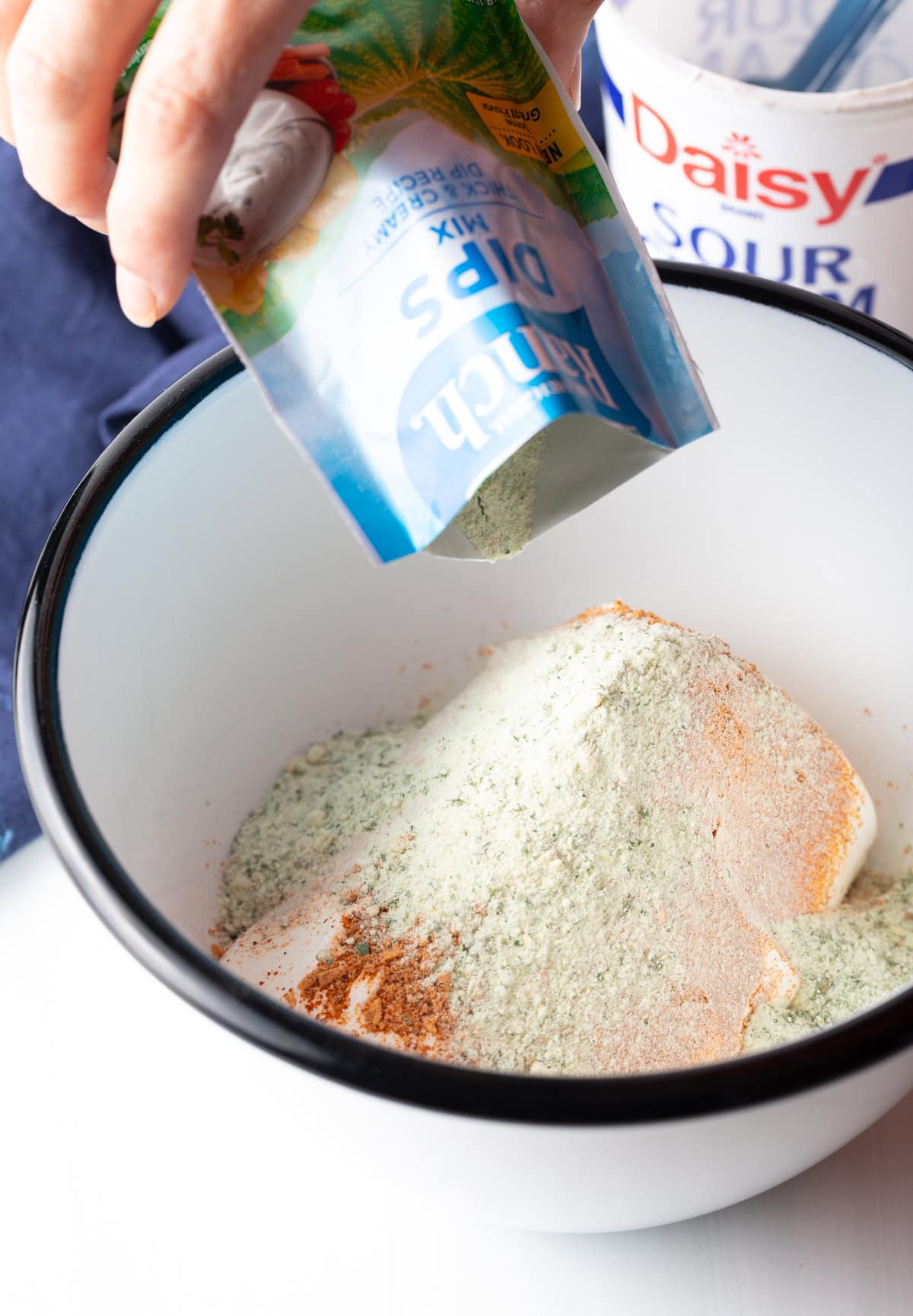 adding seasoning packets in a large white bowl