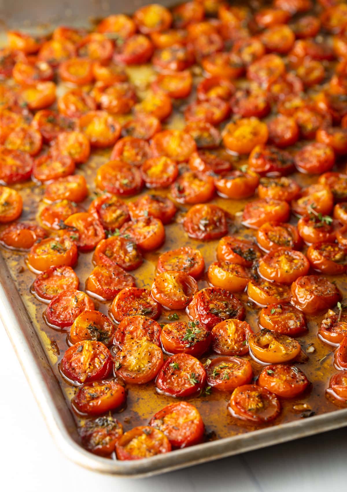 A sheet pan filled with roasted cherry tomatoes for a roasted tomato pasta recipe.