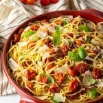 A bowl filled with roasted cherry tomato pasta topped with parmesan and fresh basil.