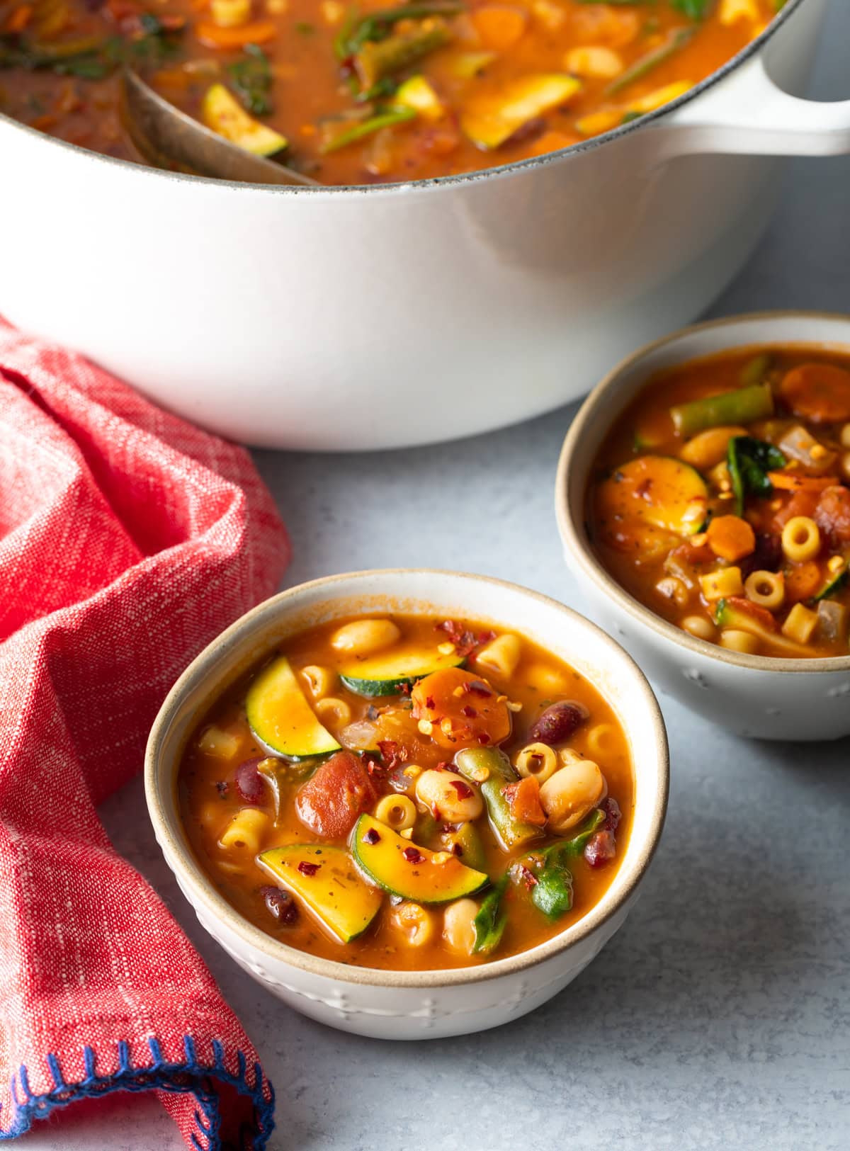 Top down view of two bowls filled with minestrone soup. 