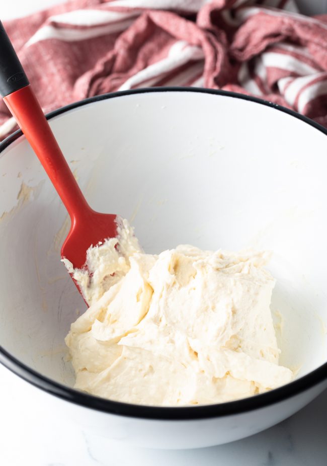 large mixing bowl with red spatula combining cream cheese mixture