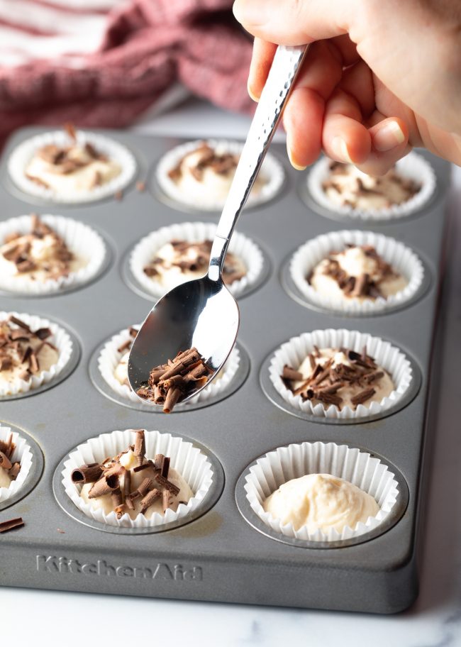 spoon adding shaved chocolate to the cream cheese bites