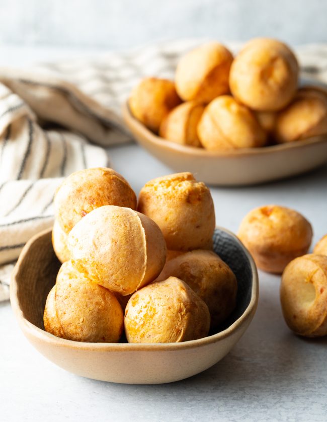 side view of a bowl filled with crispy Brazilian cheese puffs