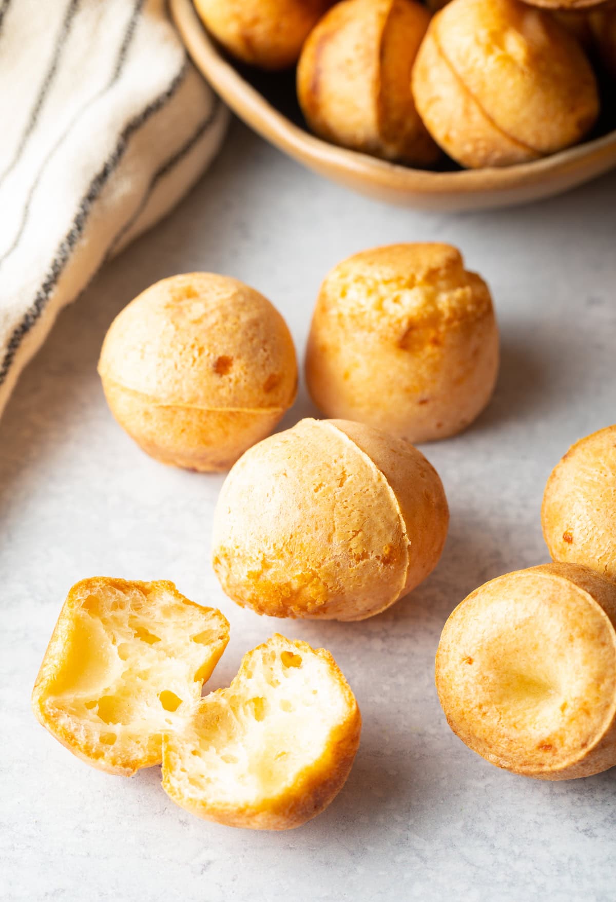 baking sheet close up view with pao de queijo and one opened to show cheesiness