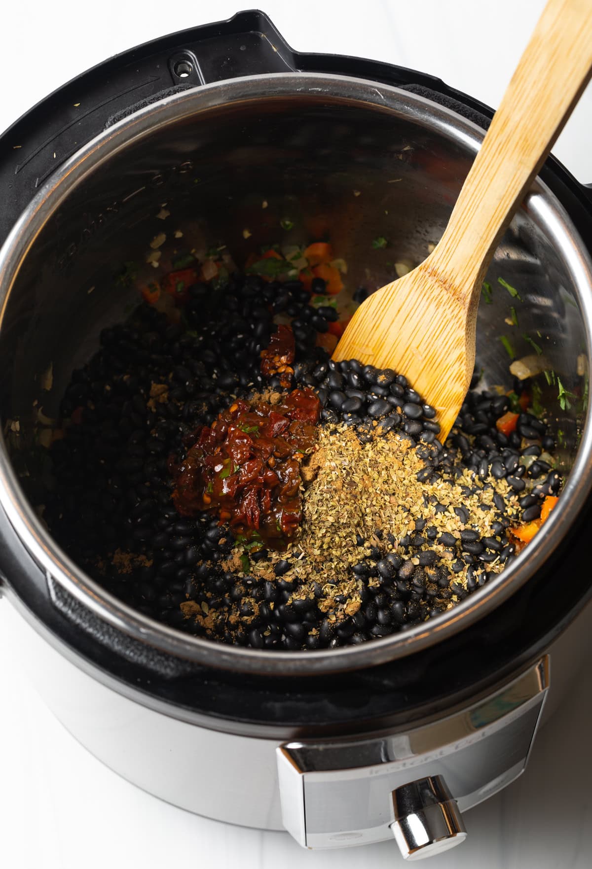 Stirring garlic, chiles, and spices in with beans in an instant pot.