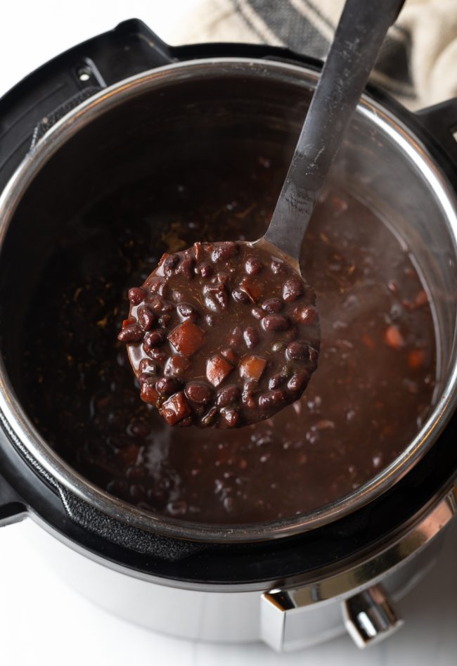 overhead view instant pot with finished black bean soup, ladleful showing towards camera