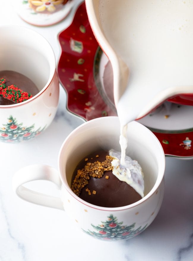 Hot milk being poured over hot chocolate bomb. 