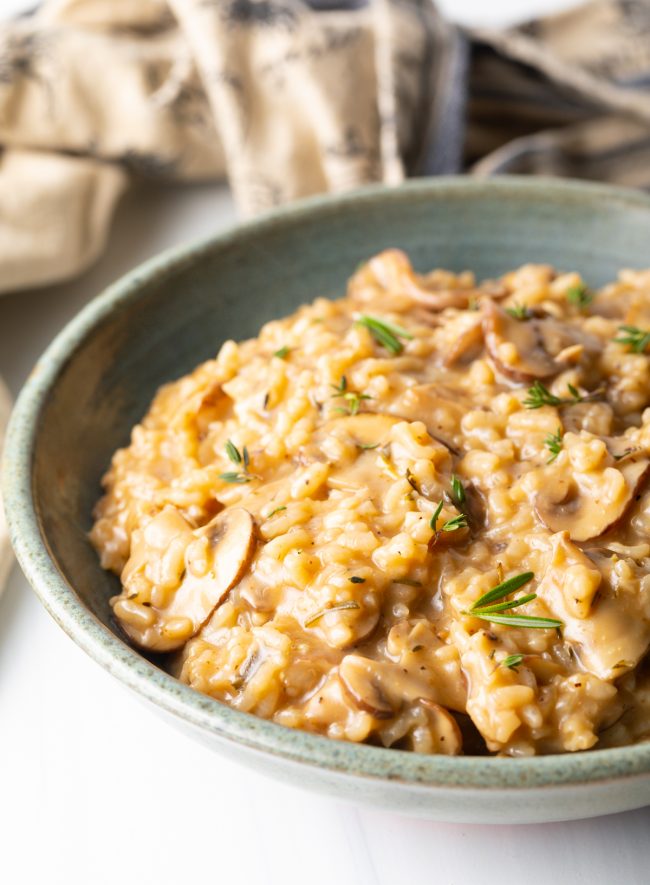 close view stone bowl with instant pot cooked mushroom risotto with fresh herbs sprinkled on top