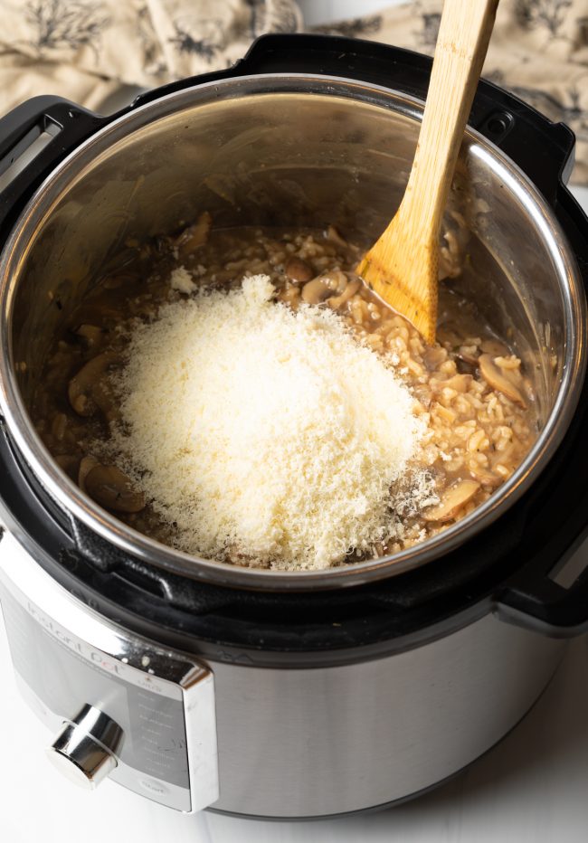 adding grated parmesan cheese to the pressure cooker
