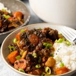 White bowl with Jamaican oxtail and beans stew and white rice.