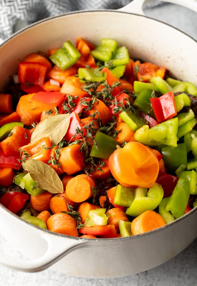 cooking pot with chopped raw veggies, carrots and peppers and seasonings