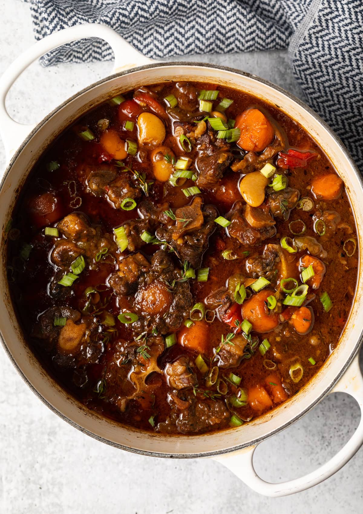 Top view white soup pot with homemade oxtail stew with veggies.