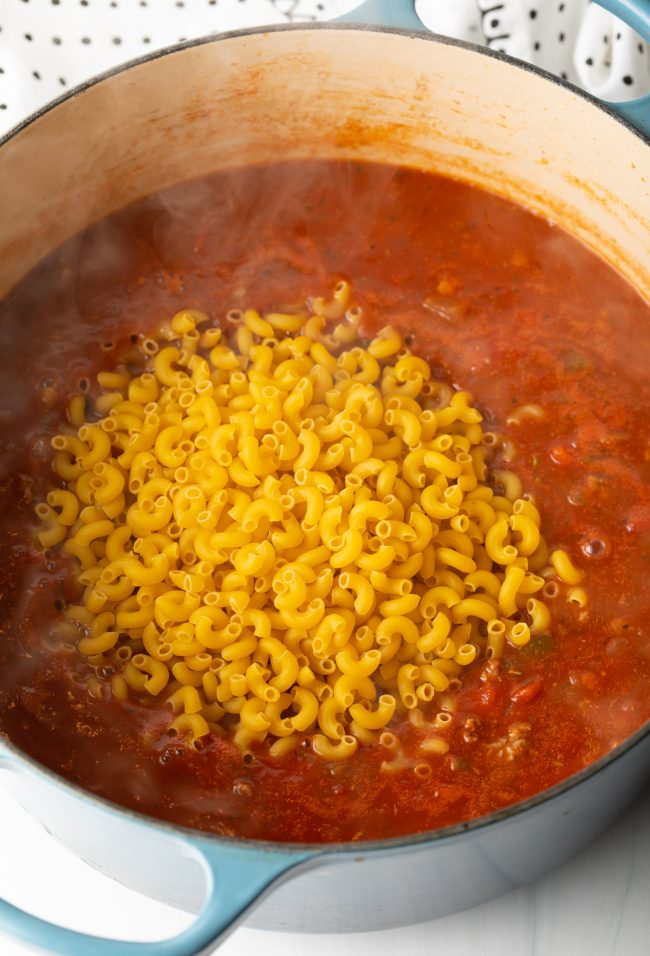 adding macaroni noodles to the pot