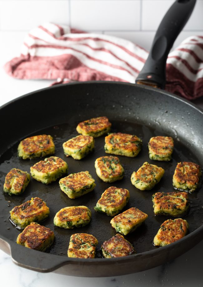 skillet with pieces of spinach ricotta dumplings pan frying
