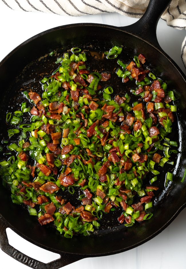 skillet with cooked chopped bacon and sliced green onions