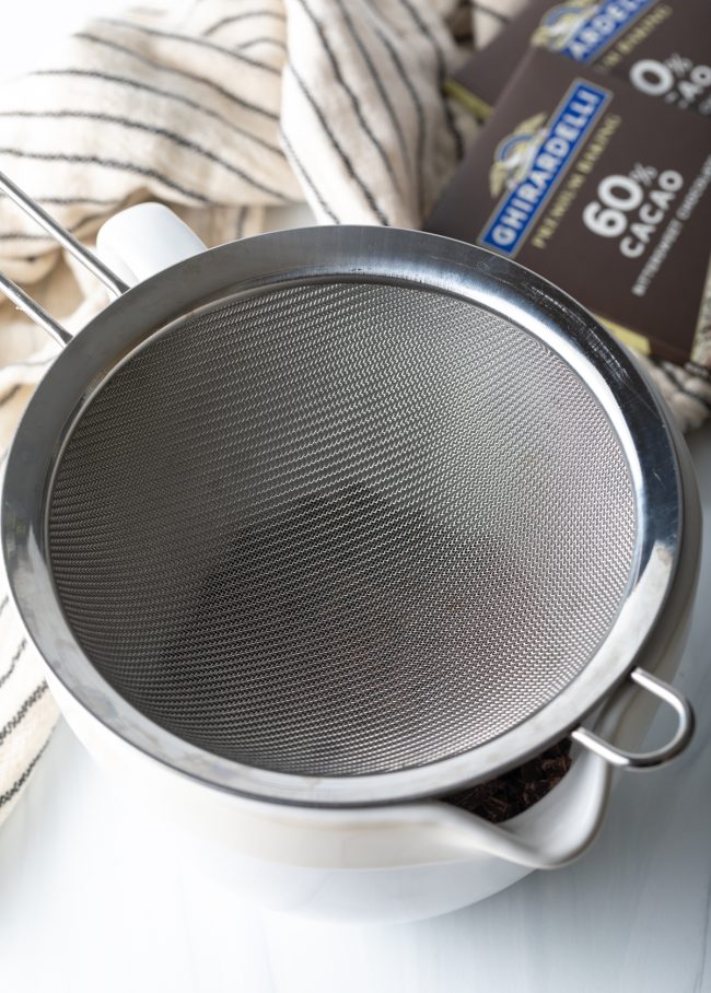 metal mesh sieve over a bowl of chopped chocolate