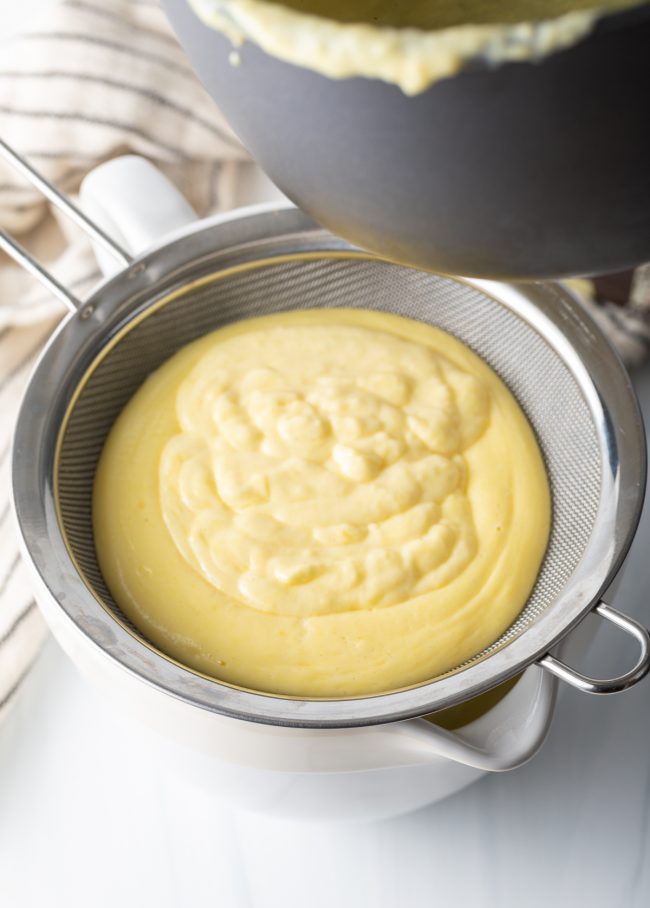 egg yolk mixture in a metal sieve over a bowl