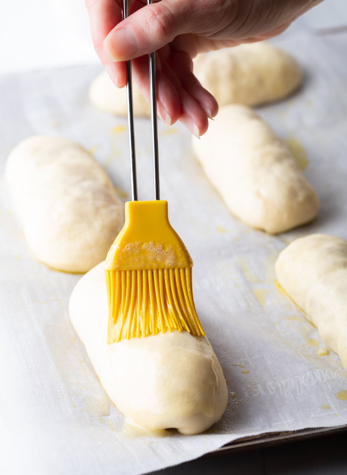 Brushing pepperoni rolls with butter.