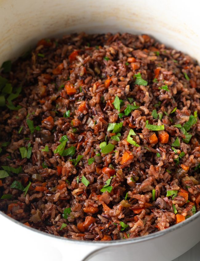 cooked wild rice dressing in a pot with chopped parsley