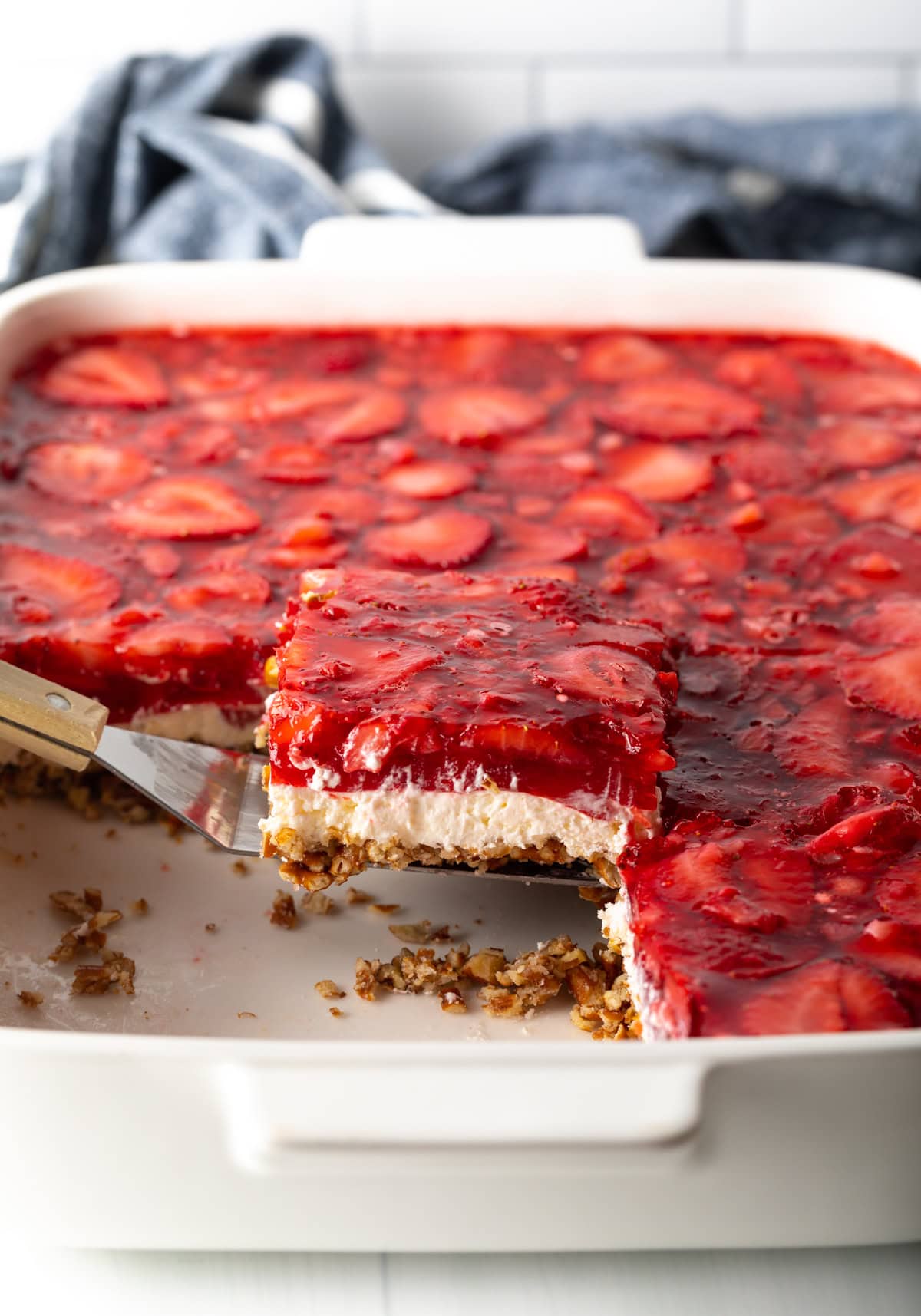 Spatula lifting a piece of jello pretzel salad dessert from the baking pan.
