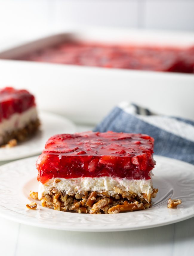 close view slice of strawberry pretzel salad with three layers on a white plate