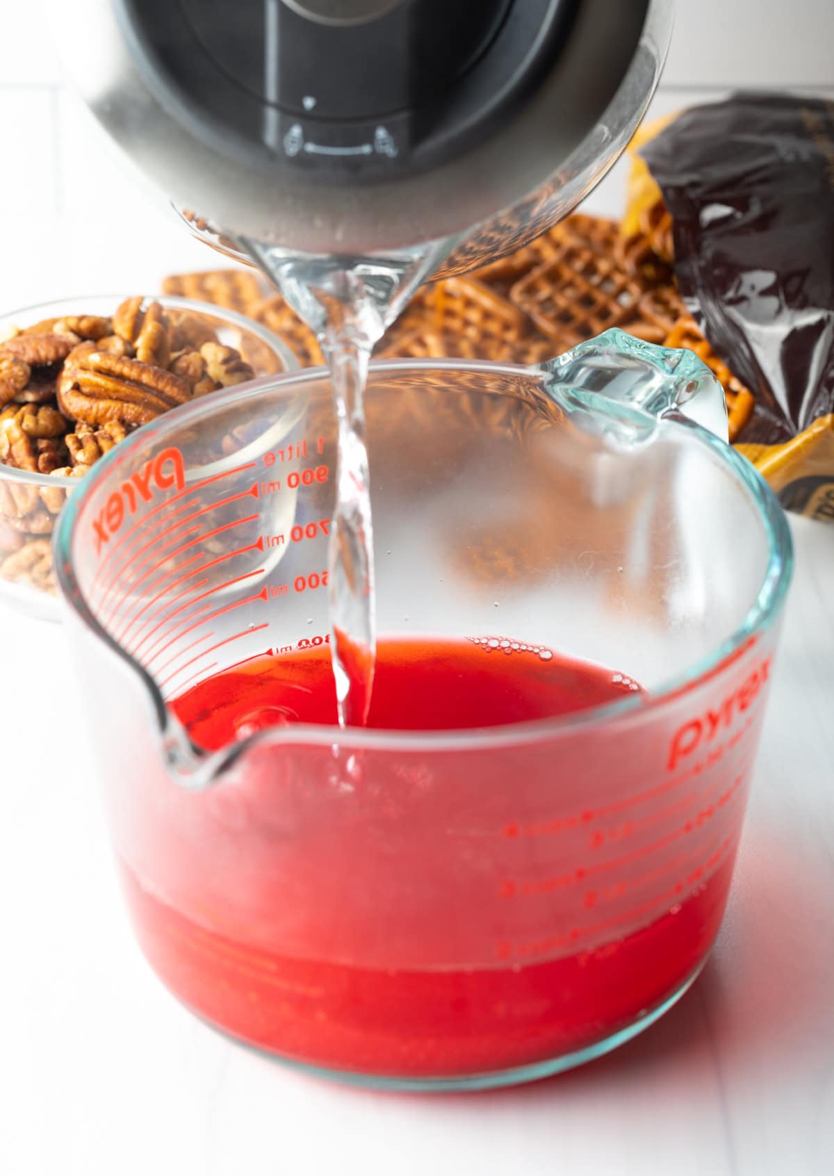 Pouring hot water into a glass measuring cup with the strawberry gelatin mix.