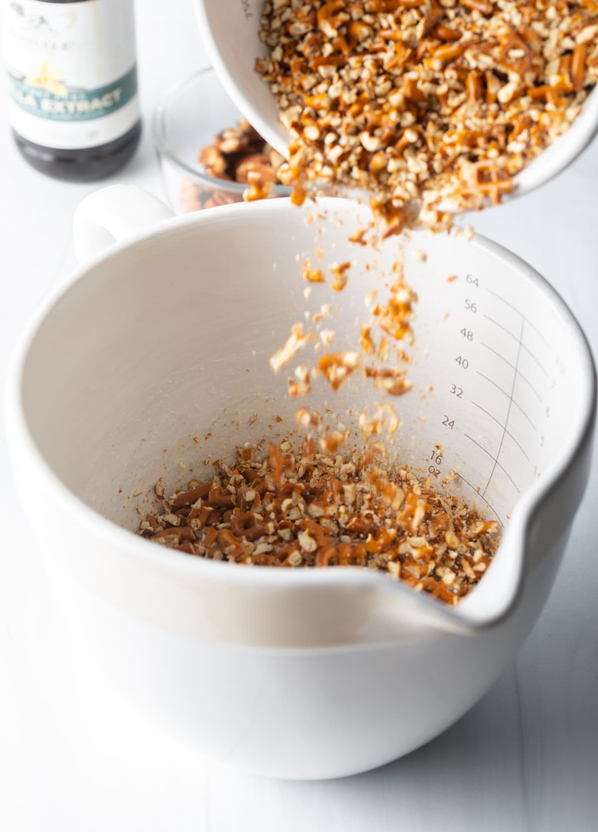 Adding crushed pretzels to a large measuring cup.