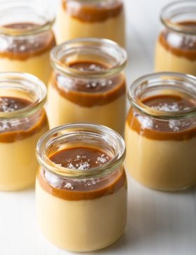 Creamy caramel flan served in small glass jars with caramel topping.