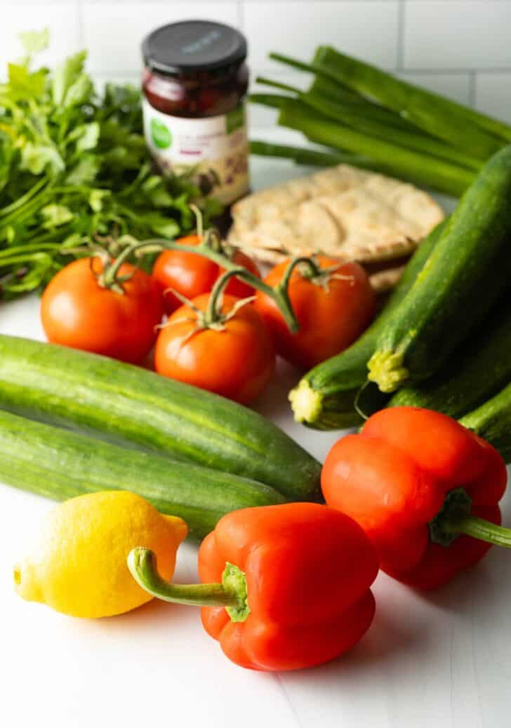 Fattoush Salad Ingredients: fresh whole red bell peppers, on the vine tomatoes, whole lemon, and several large cucumbers and zucchini.