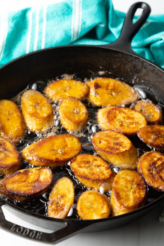 slices of plantain frying in oil in a deep skillet