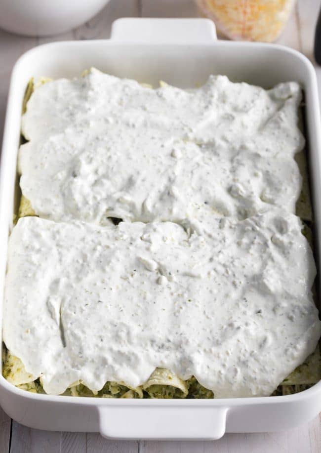 Enchiladas covered in Suiza Sauce in a baking dish right before baking. 
