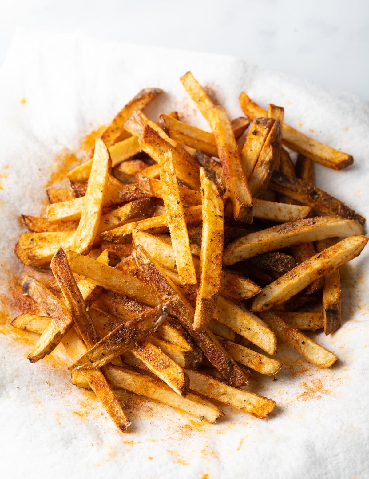 Top view sliced cajun seasoned fries on a white towel.