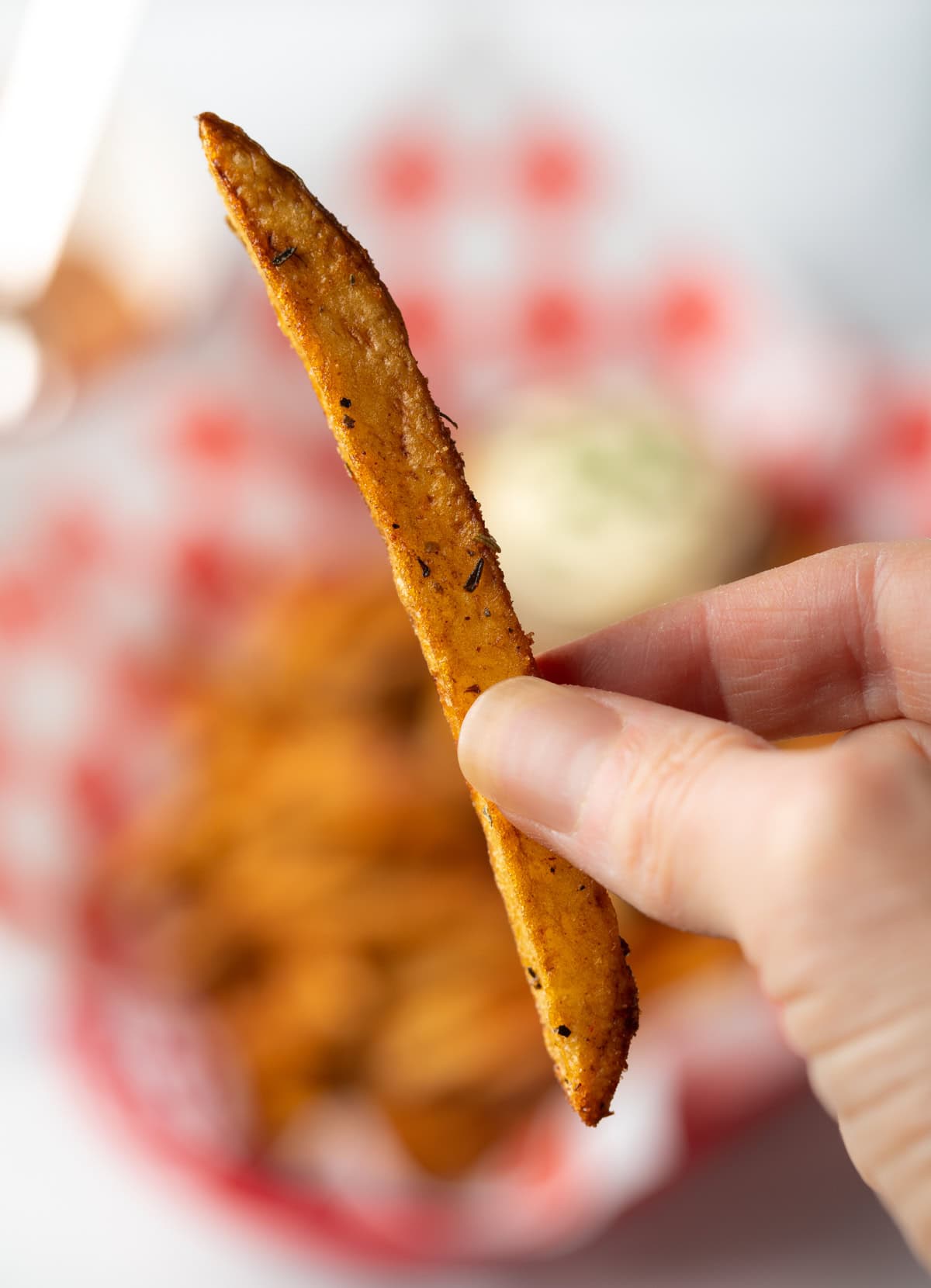 Hand holding one spiced fry to camera.