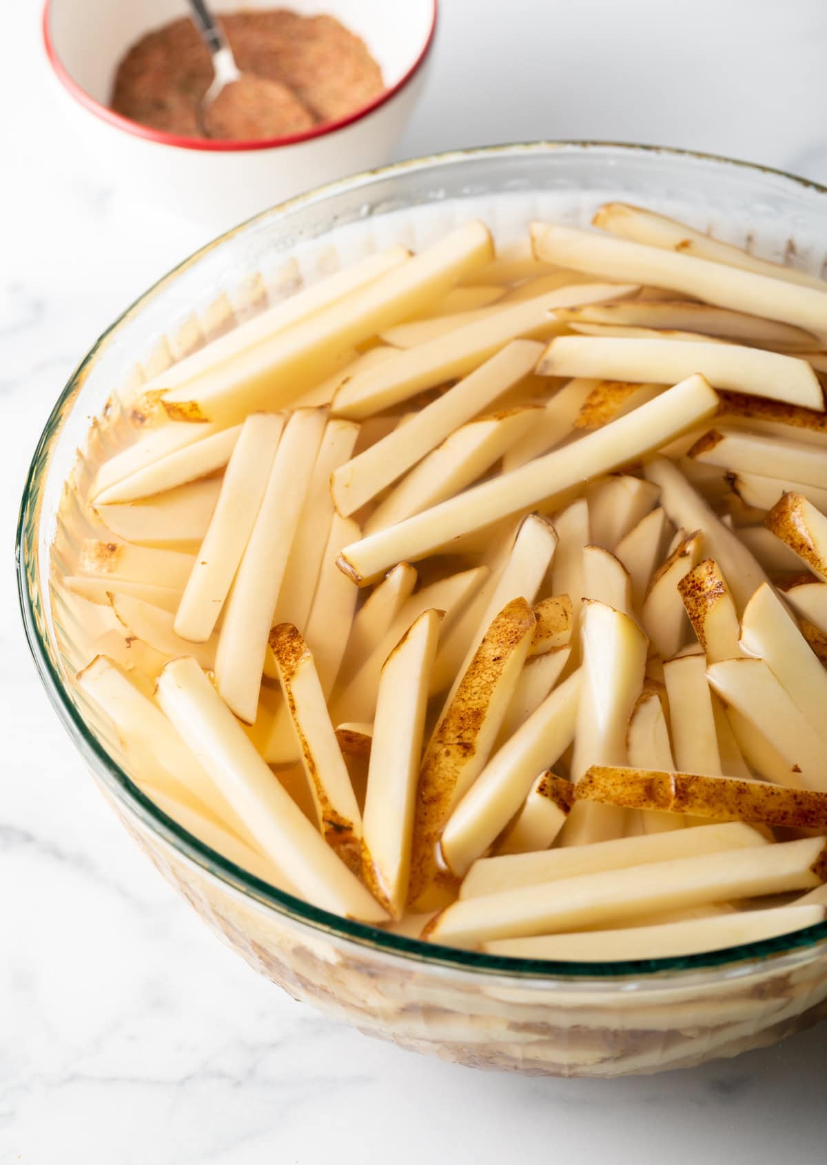 Potato slices in soaking in a bowl of water.