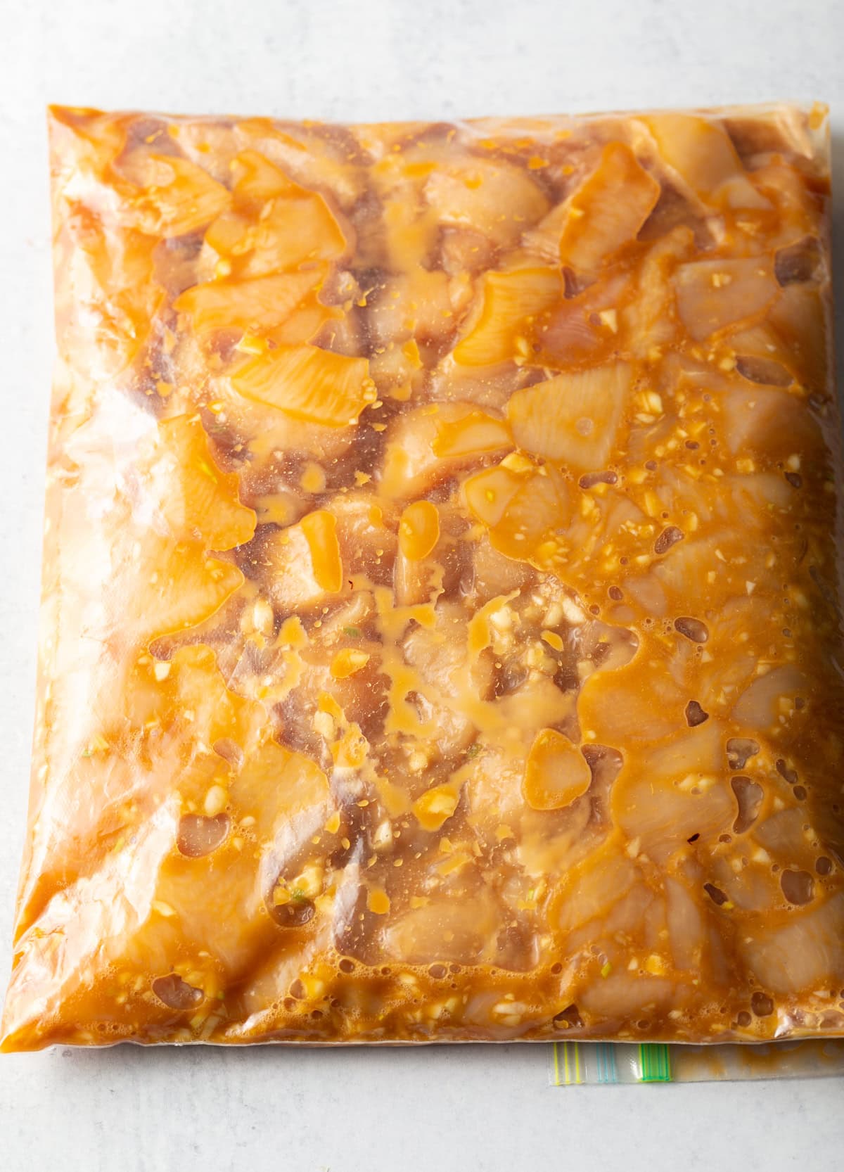 Top view plastic ziploc bag with marinating chicken pieces.