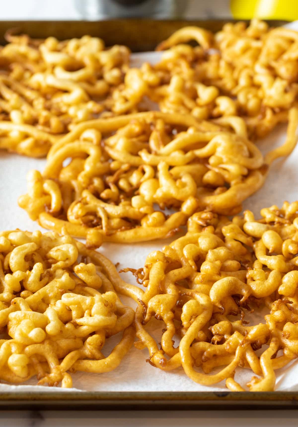 Freshly fried funnel cakes are sitting on top of paper towels to dry off excess oil.