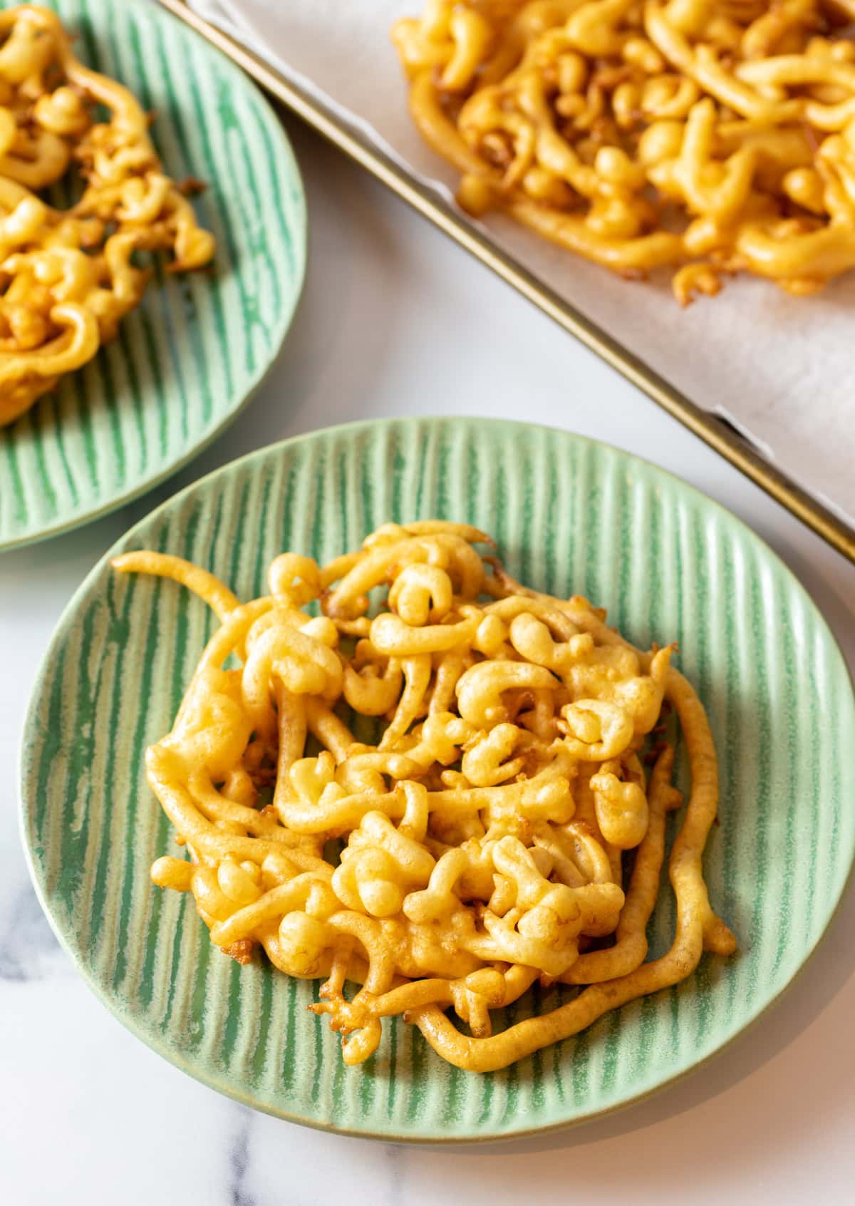 Green plate with plain fried funnel cake.